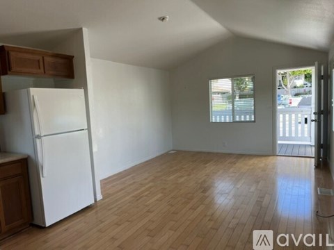 A kitchen with a white fridge and wooden floors.