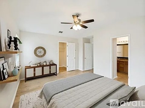 A bedroom with a bed, a fan, and a clock on the wall.