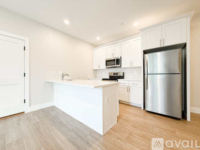 A kitchen with white cabinets and a stainless steel refrigerator.