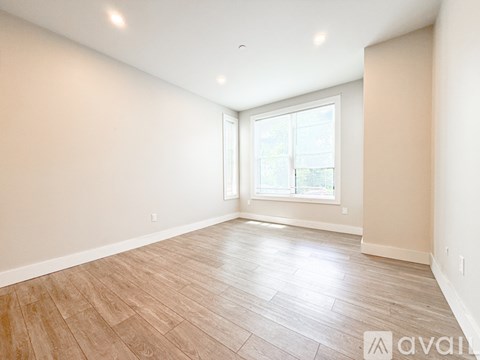 A spacious room with wooden flooring and a large window.