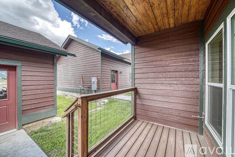 A wooden deck with a railing and a red door.