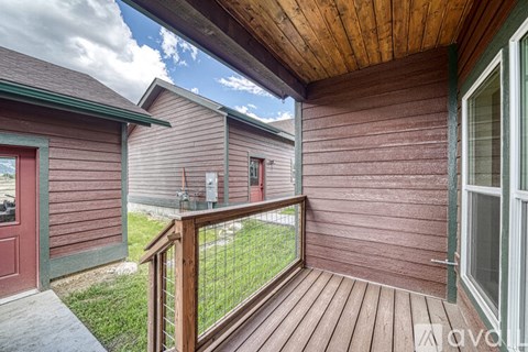 A wooden deck with a railing and a red door.