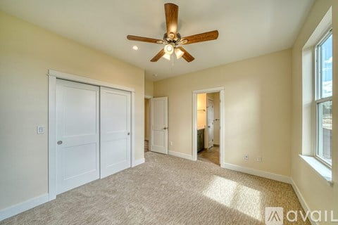 A spacious room with a ceiling fan and carpeted floor.