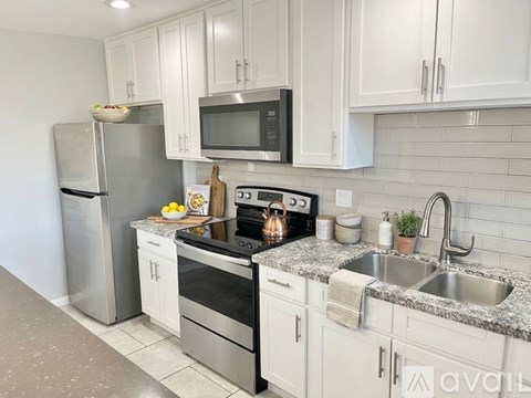A kitchen with white cabinets and a granite countertop.