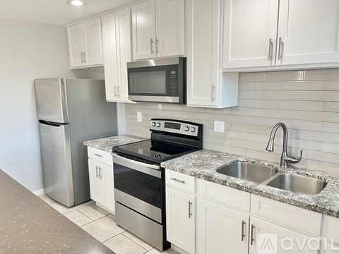 A kitchen with a stainless steel refrigerator, microwave, oven, and sink.