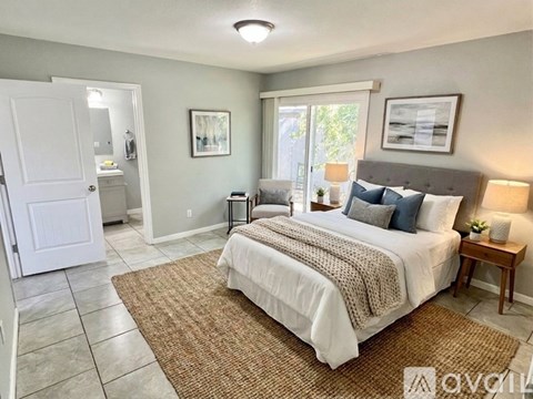 A bedroom with a large bed and a rug on the floor.