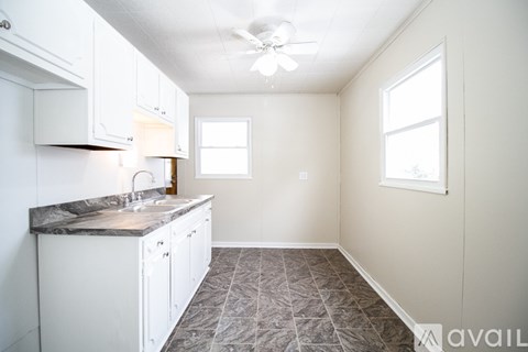 A kitchen with white cabinets and a marble countertop.