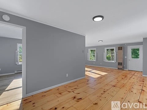 A spacious room with wooden flooring and grey walls.