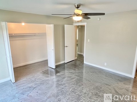 A spacious room with a ceiling fan and a door leading to another room.