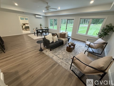 A living room with a black couch and a wooden floor.