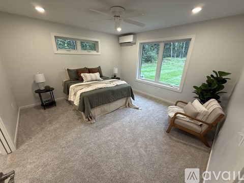 A bedroom with a bed, chair, and window.