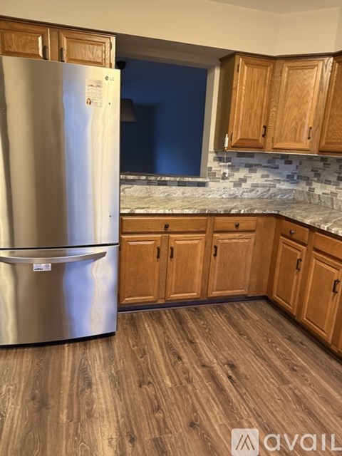 A kitchen with a stainless steel refrigerator and wooden cabinets.