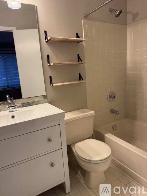 A white bathroom with a toilet, sink, and shelves.