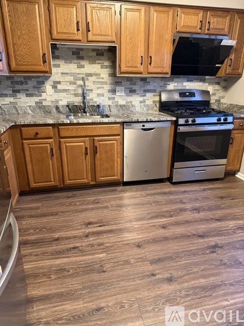 A kitchen with wooden cabinets and a stone backsplash.