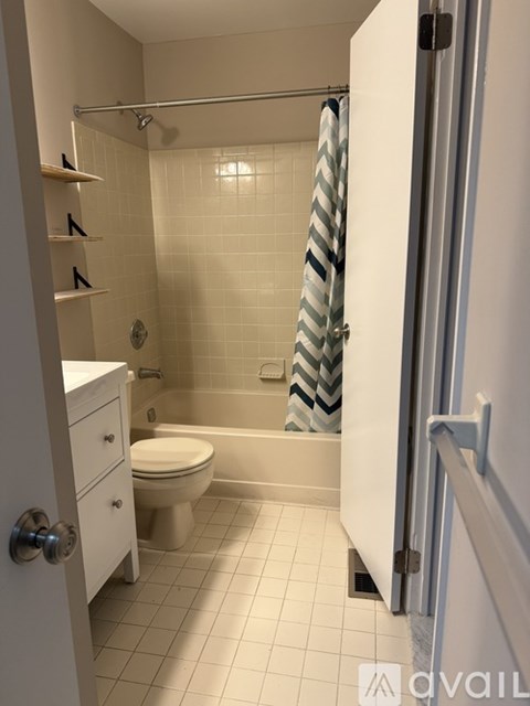 A bathroom with a toilet, a shower, and a towel rack.