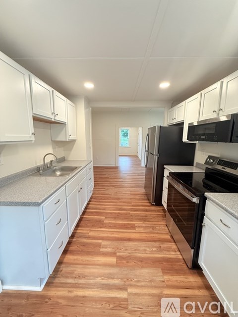 A kitchen with wooden floors and white cabinets.
