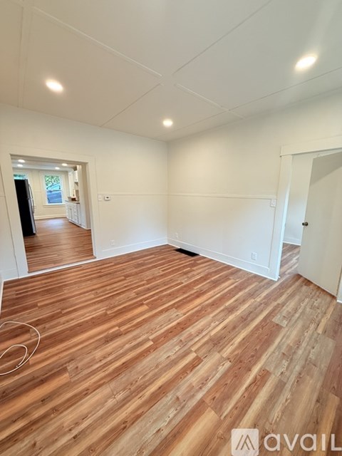 A room with wooden flooring and white walls.