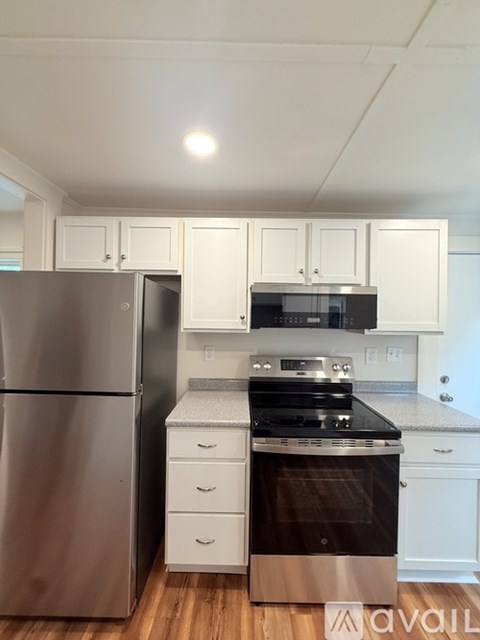 A kitchen with a stainless steel refrigerator and a stove with a microwave above it.
