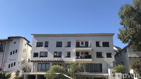 A white building with balconies and a clear blue sky in the background.