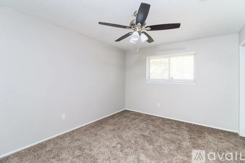 A room with wooden flooring and a white wall with a door in the background.