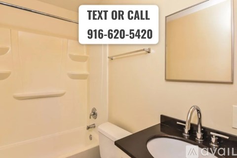 A bathroom with a sink, mirror, and bathtub with a sign that says "Text or Call 916-620-5420".