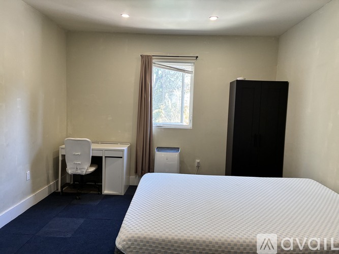 A bedroom with a bed, desk, and chair.