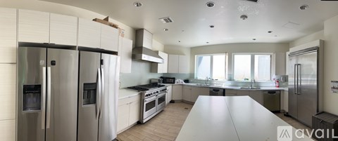 A kitchen with a table in the middle and a refrigerator on the left.