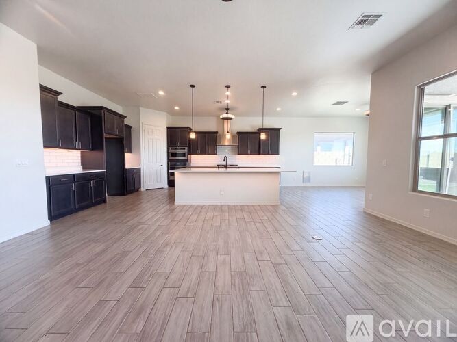 A spacious kitchen with dark wood cabinets and a white island.