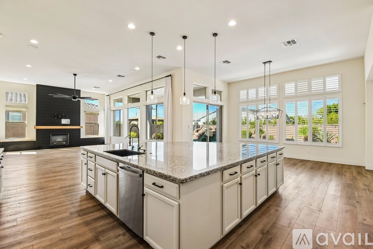 A modern kitchen with a large island and pendant lights.