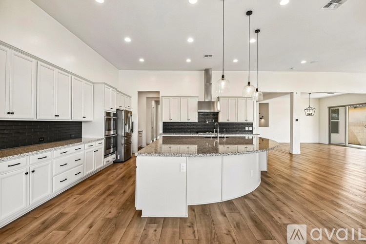 A modern kitchen with white cabinets and a wooden floor.