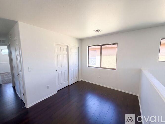 A room with white walls and dark wood flooring is available for rent.