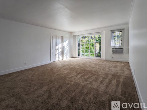 A room with carpeted floor and a window letting in natural light.