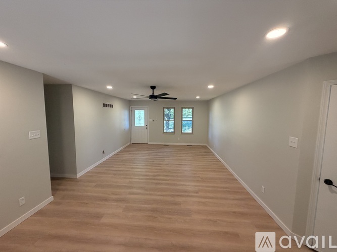 A spacious room with wooden flooring and a ceiling fan.