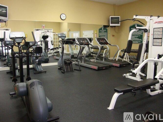 A gym with a variety of exercise equipment including treadmills, stationary bikes, and weight machines.