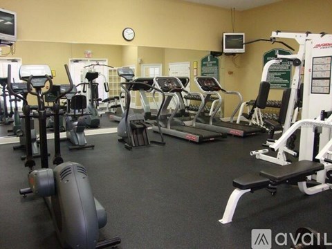 A gym with a variety of exercise equipment including treadmills, stationary bikes, and weight machines.