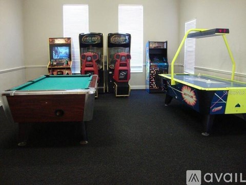 A room with a pool table, pinball machines, and a trampoline.