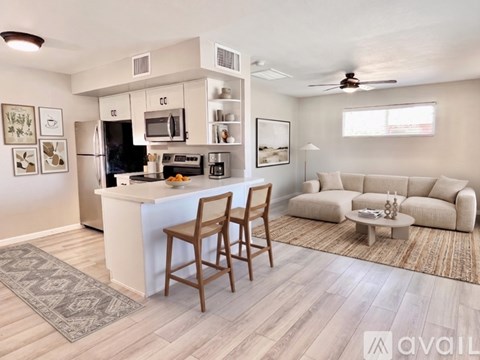 A kitchen with a bar stool and a couch in the living room.