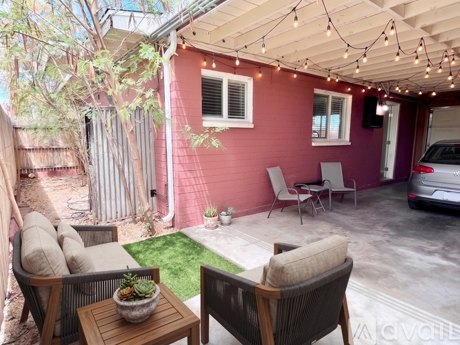 A patio with a table, chairs, and string lights.