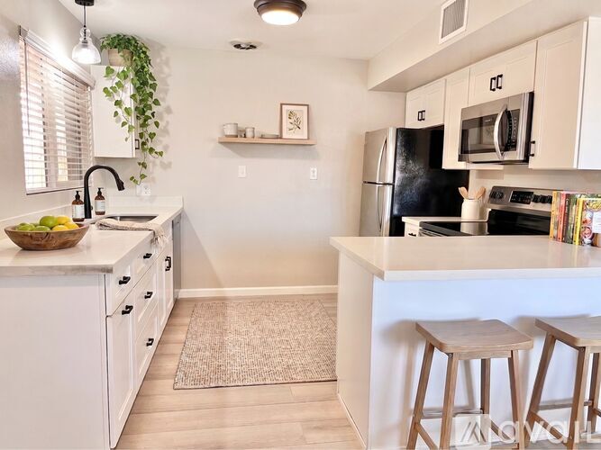 A kitchen with white cabinets and a black fridge.