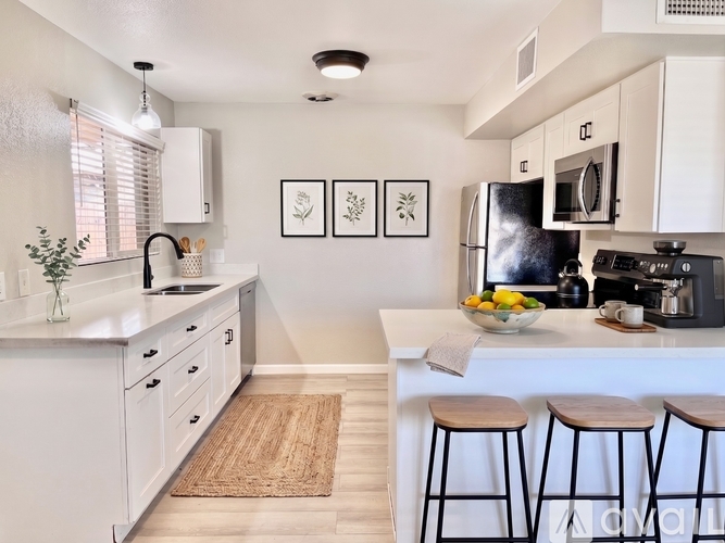 A kitchen with white cabinets and a black fridge.