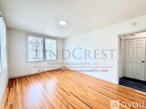 A room with wooden flooring and a window showing a view of buildings.