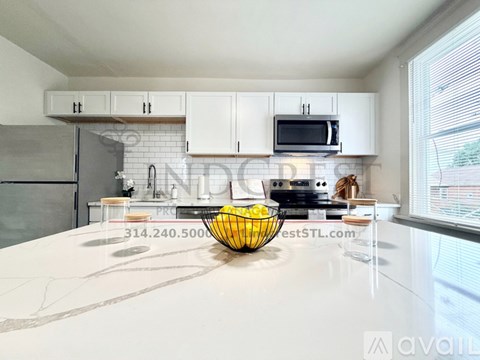 A kitchen with white cabinets and a black refrigerator.
