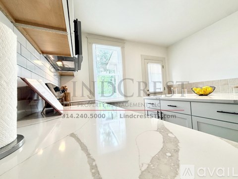A kitchen with a white countertop and a window in the background.