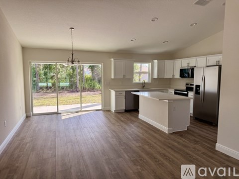 A spacious kitchen with white cabinets and a wooden floor.
