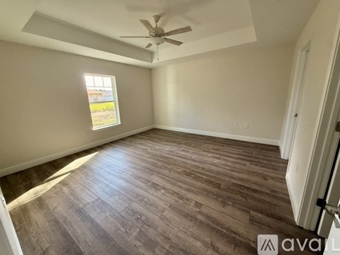 A room with a ceiling fan and a window showing a view of a building outside.