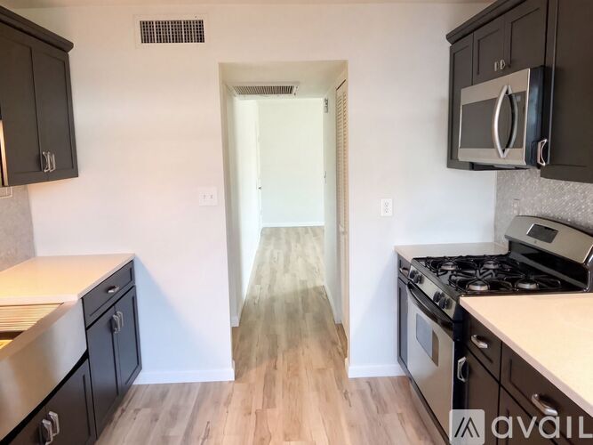 A kitchen with black cabinets and a stainless steel oven.