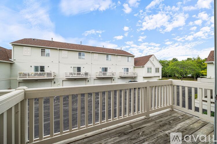 A balcony with a railing overlooks a white building with multiple windows.