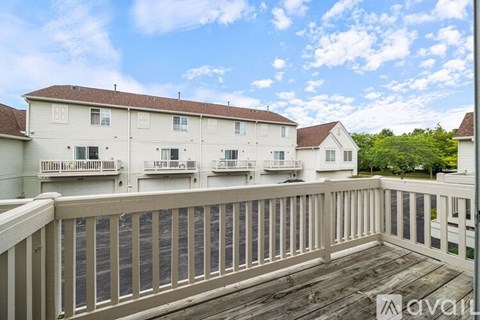 A balcony with a railing overlooks a white building with multiple windows.