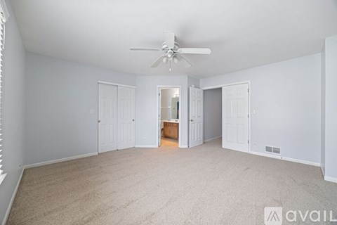 A spacious room with a ceiling fan and carpeted floor.