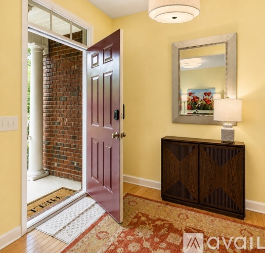 A room with a purple door and a wooden cabinet with a mirror above it.